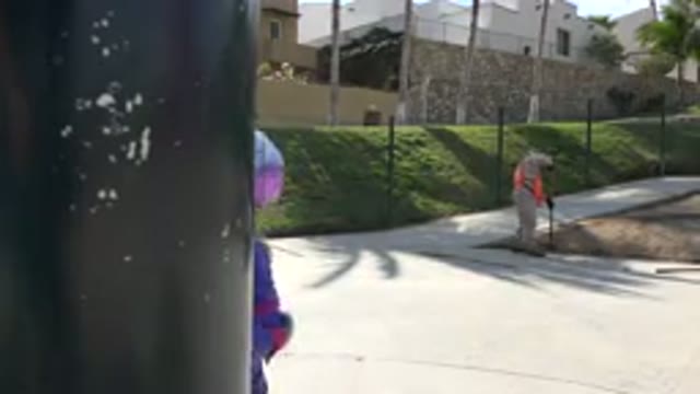 LOS CABOS MEXICO-2019: Little Girl On Scooter Peeks Around Post As Maintenance Worker