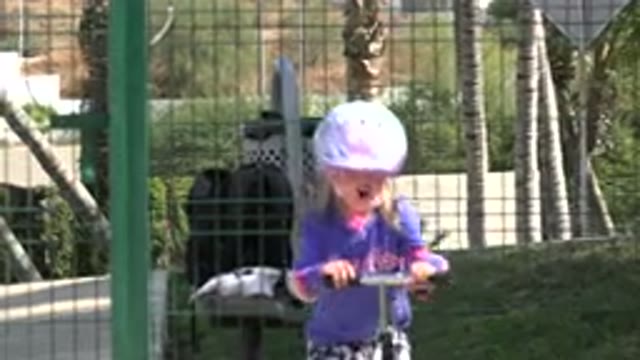 LOS CABOS MEXICO-2019: Little Blonde Girl in Helmet Rides Scooter Towards Camera