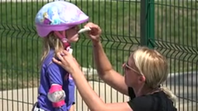 LOS CABOS MEXICO-2019: Woman Applies Sunscreen To A Child Wearing A Helmet And Pads