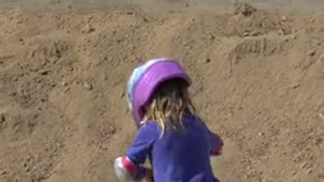 LOS CABOS MEXICO-2019: Child Wearing Helmet and Elbow Pads Riding Scooter Down Sandy Hillside