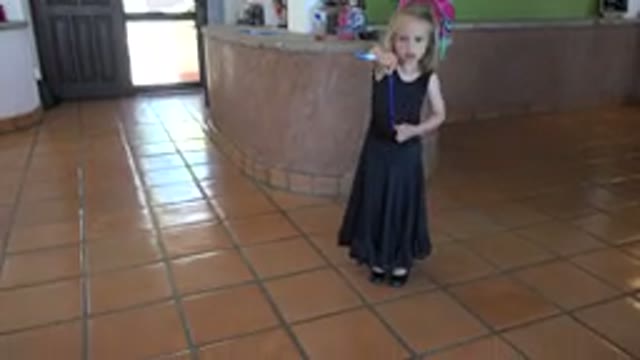 LOS CABOS MEXICO-2019: Little Girl in Black Dress Fidgets with Blue Ribbon