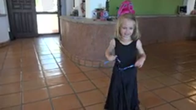 LOS CABOS MEXICO-2019: A Little Girl in a Black Huffed Dress Passes a Blue Object