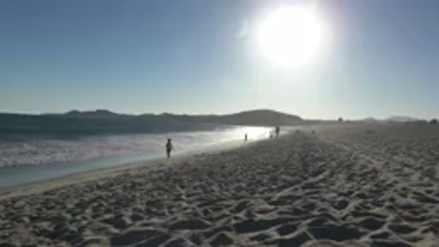 LOS CABOS MEXICO-2019: Beach With Bathers Walking On The Shore With The Sun Low