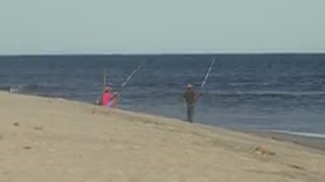 LOS CABOS MEXICO-2019: Two People Fishing On The Beach On A Clear Day