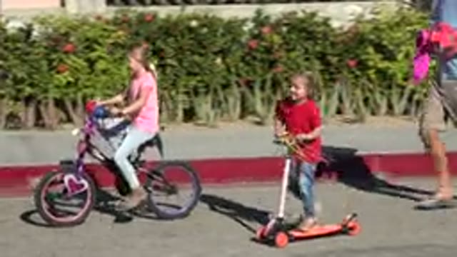 LOS CABOS MEXICO-2019: Children Riding Bicycles and Scooters on Sidewalk