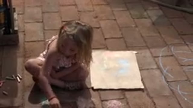 LOS CABOS MEXICO-2019: Girl Wearing Pink Sunsuit Sits On Brick Floor Using Chalk