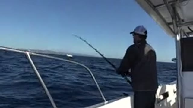LOS CABOS MEXICO-2019: Man Wearing Grey Jacket Uses Black Fishing Pole Over Side