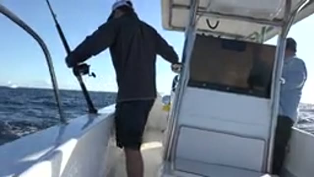 LOS CABOS MEXICO-2019: Man Wearing Grey Shirt Grabs Black Fishing Pole While Standing on White Boat