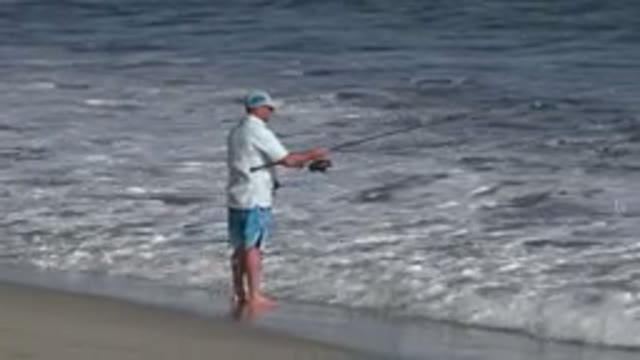 LOS CABOS MEXICO-2019: Fisherman Reels In His Lure As Woman And Girl Pass Behind