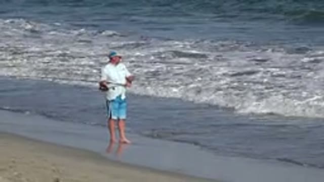 LOS CABOS MEXICO-2019: Man Casts Large Fishing Rod Into The Waves From The Beach