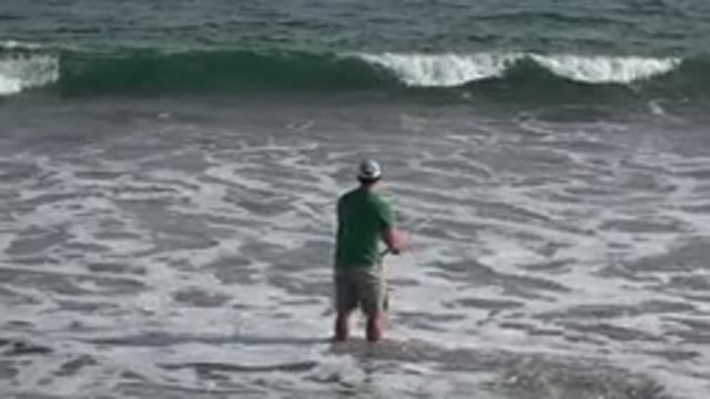 LOS CABOS MEXICO-2019: A Green Shirt Wearing Man Standing In Shallow Wavy Waters