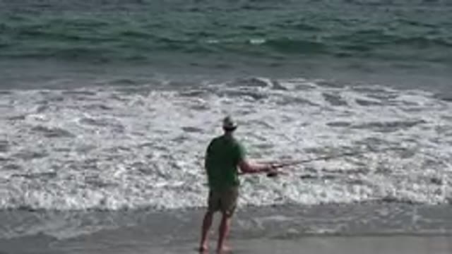 LOS CABOS MEXICO-2019: Man In Green Shirt And Tan Shorts Fishing In The Ocean