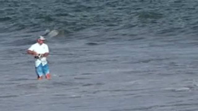 LOS CABOS MEXICO-2019: Man Fishing In Surf Reeling Fish Into Beach