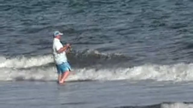 LOS CABOS MEXICO-2019: Man Fishing In The Ocean With Waves Splashing Against His Legs