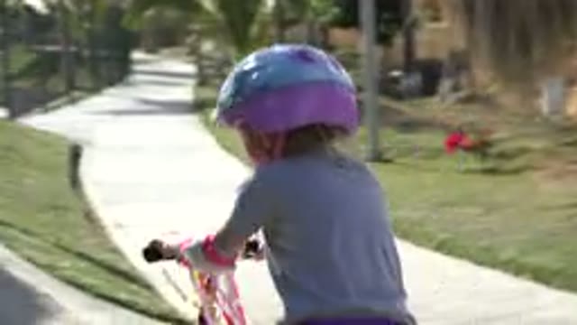 SAN JOSE DEL CABO MEXICO-2019: Child Wearing A Helmet Riding A Scooter Uphill On Paved Path