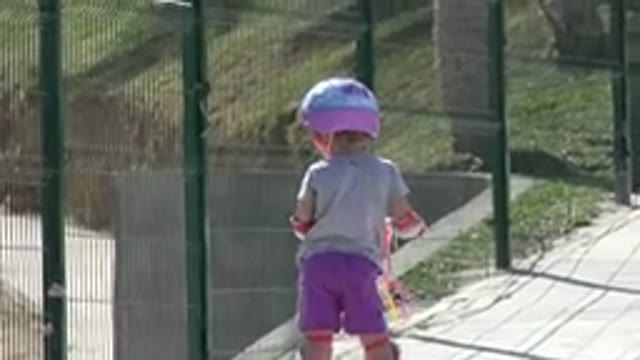 SAN JOSE DEL CABO MEXICO-2019: Little Girl in Purple Shorts Rides Scooter Through Green Gate