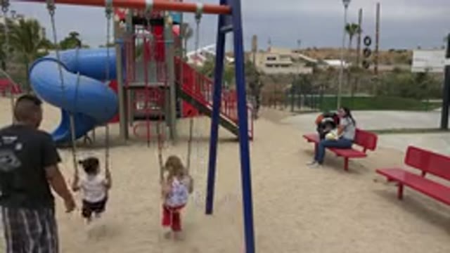 SAN JOSE DEL CABO MEXICO-2019: Girl Wearing Red Pants Swings On Blue And Red Swing Set