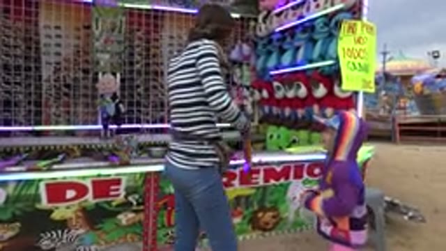 SAN JOSE DEL CABO MEXICO-2019: Shooting Booth Attendant Helps Small Child With