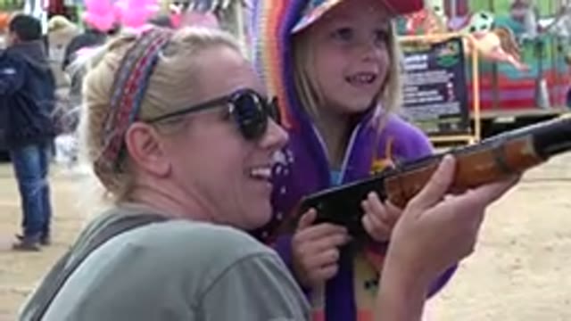 SAN JOSE DEL CABO MEXICO-2019: Girl Wearing Purple Jacket Holds Brown Toy Rifle