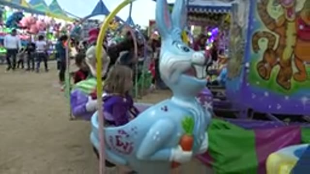 SAN JOSE DEL CABO MEXICO-2019: Girl Wearing Purple Jacket Sits on Blue Bunny Ride
