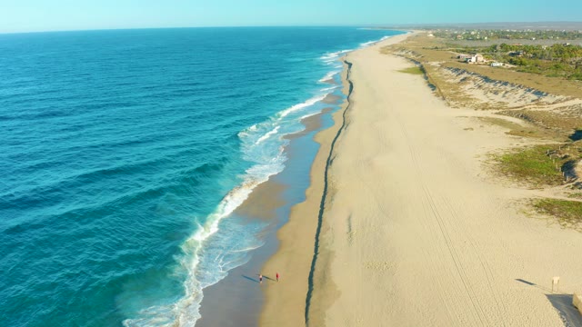 TODOS SANTOS BCS MEXICO-2021: Beachgoer Strolling on Sandy Shore Beside Rolling Ocean Waves
