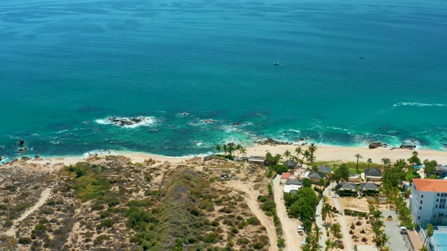 MARQUIS LOS CABOS MEXICO-2021: Waves Crashing on Rocky Shore with Coastal Buildings