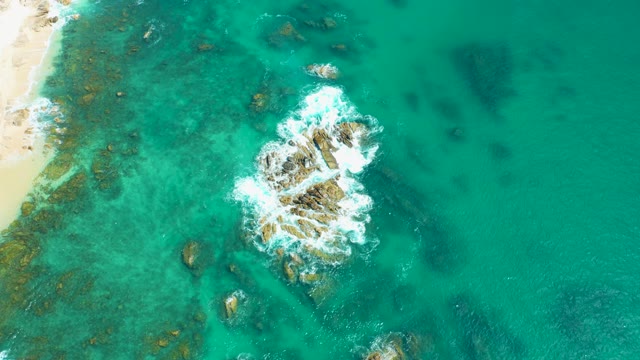 MARQUIS LOS CABOS MEXICO-2021: Waves Crashing Against Rocky Outcrops in Clear Turquoise Water