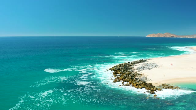 MARQUIS LOS CABOS MEXICO-2021: Waves Crashing on Rocky Shore with Distant Island