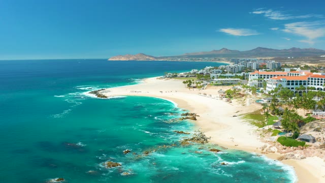 MARQUIS LOS CABOS MEXICO-2021: Waves Crashing on Sandy Shore with Coastal Buildings