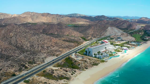 MARQUIS LOS CABOS MEXICO-2021: Coastal Highway Traffic Along Sandy Beach and Arid Mountains