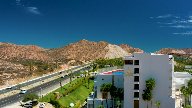 MARQUIS LOS CABOS MEXICO-2021: Highway Traffic Moving Past Desert Mountains and Building