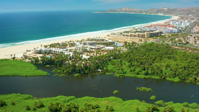SAN JOSE DEL CABO BCS MEXICO-2021: Waves Rolling Onto Sandy Beach with Lagoon and Greenery