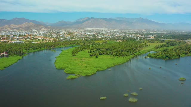 SAN JOSE DEL CABO BCS MEXICO-2021: River with Lush Island and Distant Cityscape