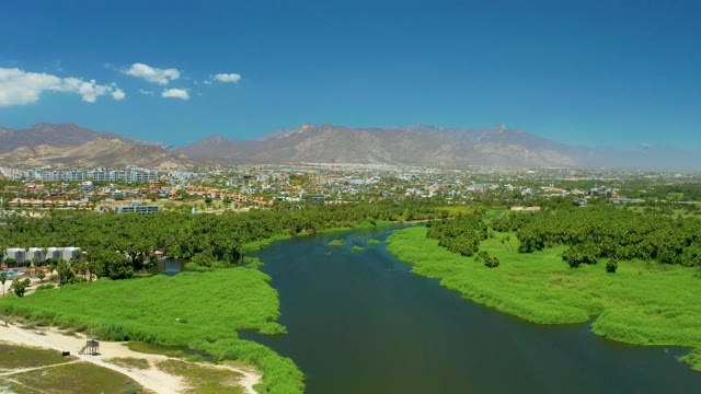SAN JOSE DEL CABO ESTUARY BCS MEXICO-2021: Lush River Banks and Distant Cityscape