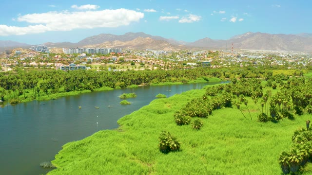 SAN JOSE DEL CABO ESTUARY BCS MEXICO-2021: River with Green Banks and Distant City From Above