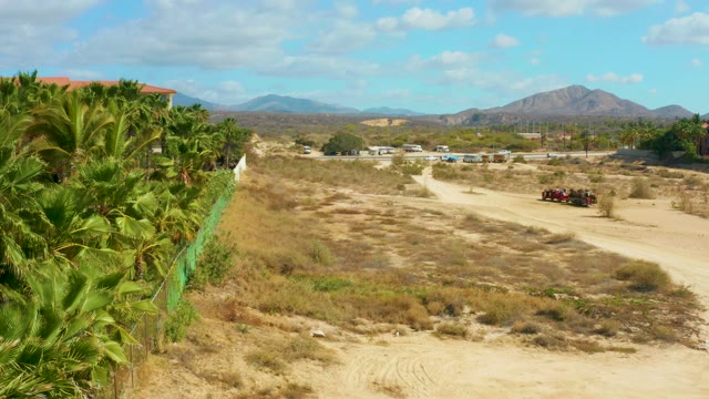 HILTON LOS CABOS MEXICO-2021: Arid Dirt Road with Palm Trees and Passing Vehicle
