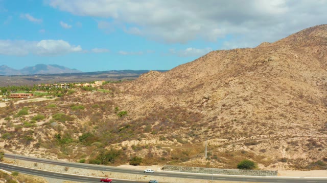 HILTON LOS CABOS MEXICO-2021: Vehicles Moving on a Highway Through Dry Hilly Terrain