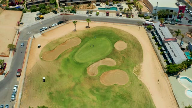 SAN JOSE DEL CABO BCS MEXICO-2021: Golf Green Surrounded by Sand Traps and Moving Vehicles