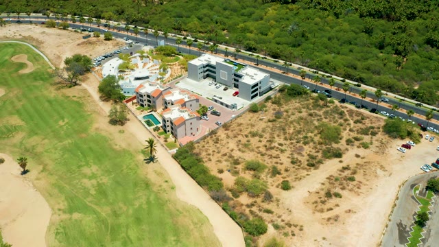 SAN JOSE DEL CABO BCS MEXICO-2021: Vehicles Moving on Road Near Golf Course and Resort Building