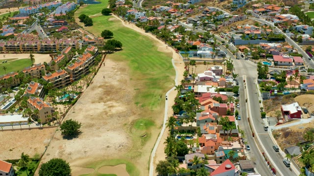 SAN JOSE DEL CABO BCS MEXICO-2021: Vehicles Moving Along a Road Beside Residential Green Space
