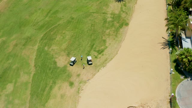 SAN JOSE DEL CABO BCS MEXICO-2021: Person and Golf Carts Moving on Grassy Field and Sandy Path