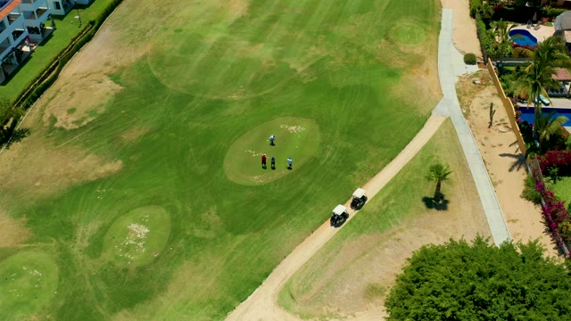 SAN JOSE DEL CABO BCS MEXICO-2021: Golfers Moving on a Green with a Cart Nearby