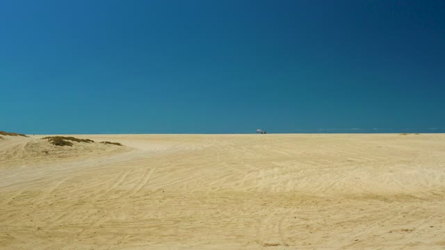 LA LAGUNA BEACH LOS CABOS MEXICO-2021: Sandy Desert Landscape with Distant Vehicle in Motion