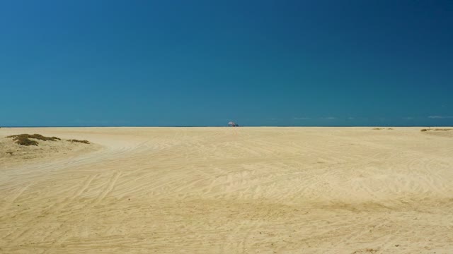 LA LAGUNA BEACH LOS CABOS MEXICO-2021: Sandy Beach with Distant Figure Moving Toward Camera