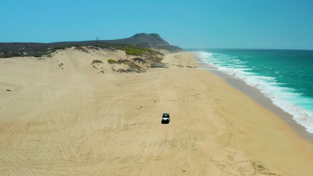 LA LAGUNA BEACH LOS CABOS MEXICO-2021: Vehicles Traversing Sandy Beach Beside Ocean Waves