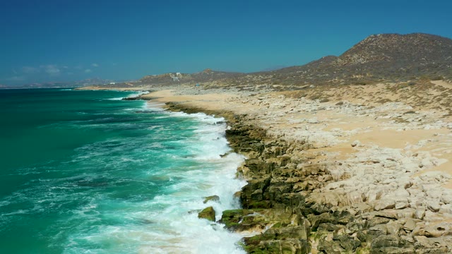 LA LAGUNA BEACH LOS CABOS MEXICO-2021: Waves Crashing on Rocky Shoreline with Sandy Beach