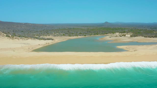 LA LAGUNA BEACH LOS CABOS MEXICO-2021: Waves Breaking on Sandy Shore with Lagoon