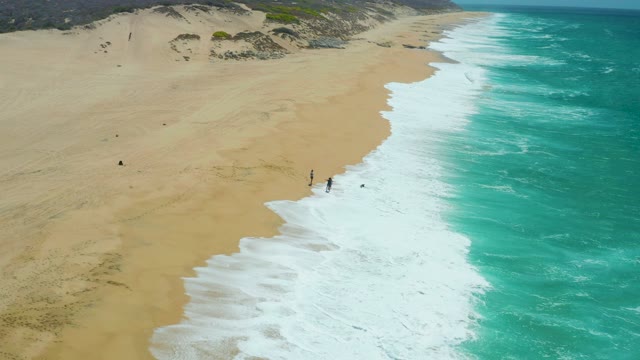 LA LAGUNA BEACH LOS CABOS MEXICO-2021: Beachgoers Strolling near Crashing Ocean Waves