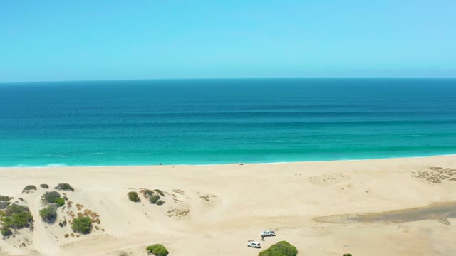 LA LAGUNA BEACH LOS CABOS MEXICO-2021: SUV Driving Across Sandy Beach Dunes by Ocean