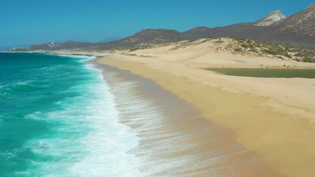 LA LAGUNA BEACH LOS CABOS MEXICO-2021: Waves Rolling Onto Sandy Beach with Lagoon